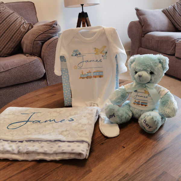 Personalised Baby Boy Gift Set featuring a blanket, sleepsuit, teddy bear, and personalized teddy bear t-shirt. Presented in a stylish gift box, perfect for celebrating the arrival of the new bundle of joy.